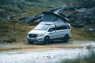 Rhön Camp The Pace Campervan auf Mercedes Vito mit geöffnetem Aufstelldach in bergiger Landschaft