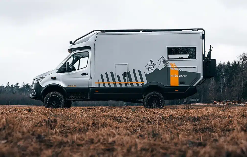 Seitenansicht des Rhön Camp The Renegade Campervans auf Mercedes Sprinter Basis, stehend auf einer Wiese vor bewaldetem Hintergrund.