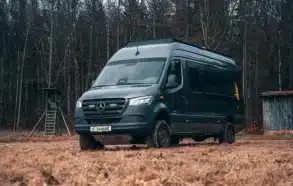 Rhön Camp The Savage Kastenwagen auf Mercedes Sprinter Basis steht auf einer Wiese vor einem Wald.