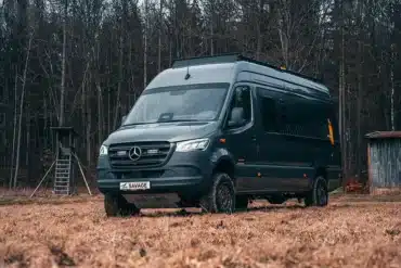 Rhön Camp The Savage Kastenwagen auf Mercedes Sprinter Basis steht auf einer Wiese vor einem Wald.