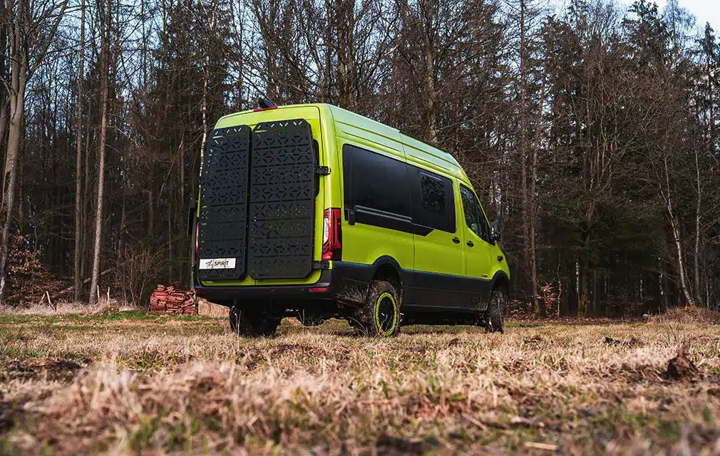 Rhön Camp THE SPIRIT Campervan in leuchtendem Grün steht auf einer Lichtung am Waldrand