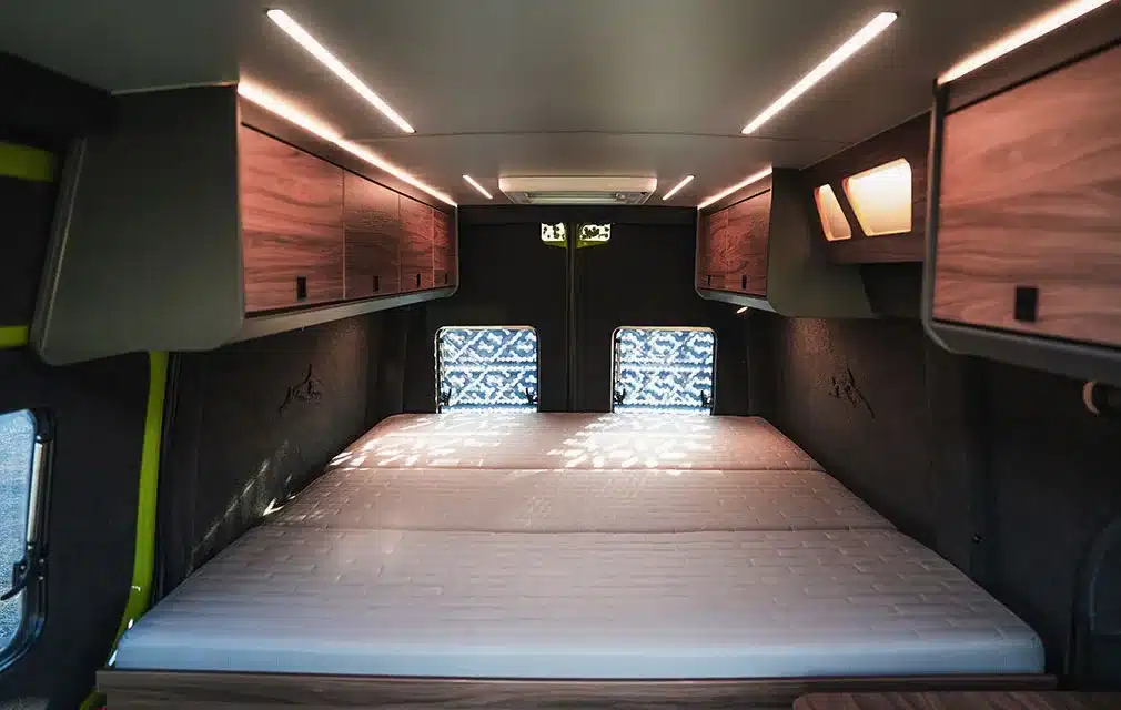 Schlafbereich im Rhön Camp THE SPIRIT Campervan mit großem Doppelbett, LED-Beleuchtung und Hängeschränken
