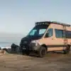 Rob Machado Surf Van Rogue Wave, ein ausgebauter Mercedes Sprinter mit Offroad-Elementen, steht am Strand vor dem Meer