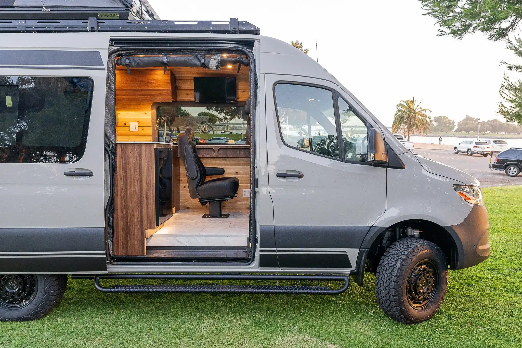 Seitenansicht eines geöffneten Rogue Blanc Campervans mit luxuriösem Innenausbau und drehbarem Sitz