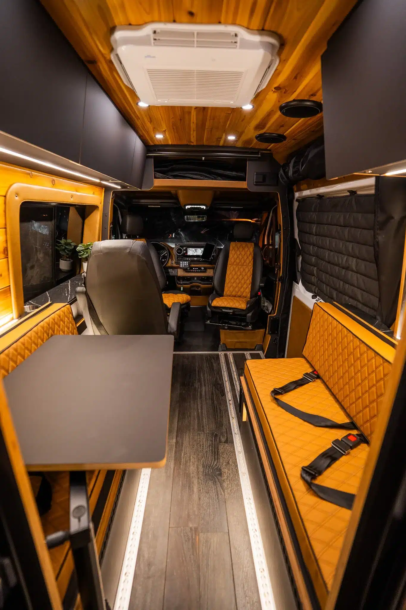 Blick in den hochwertig ausgebauten Innenraum eines Rogue Stratos Campervans mit Ledersitzen, Holzdecke, Tisch und moderner Beleuchtung