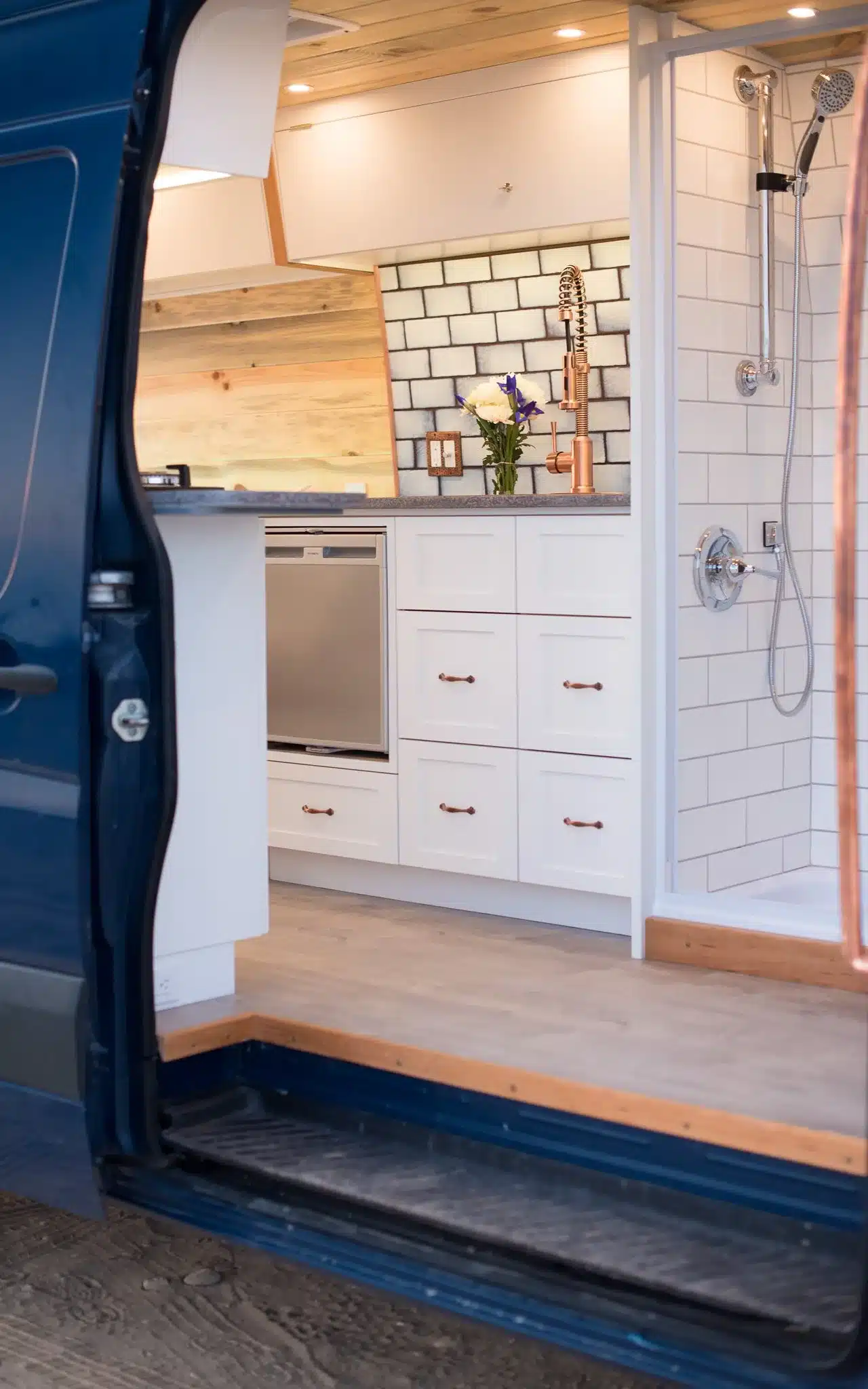 Blick in den Innenraum eines ausgebauten Vans mit moderner Küche und Dusche