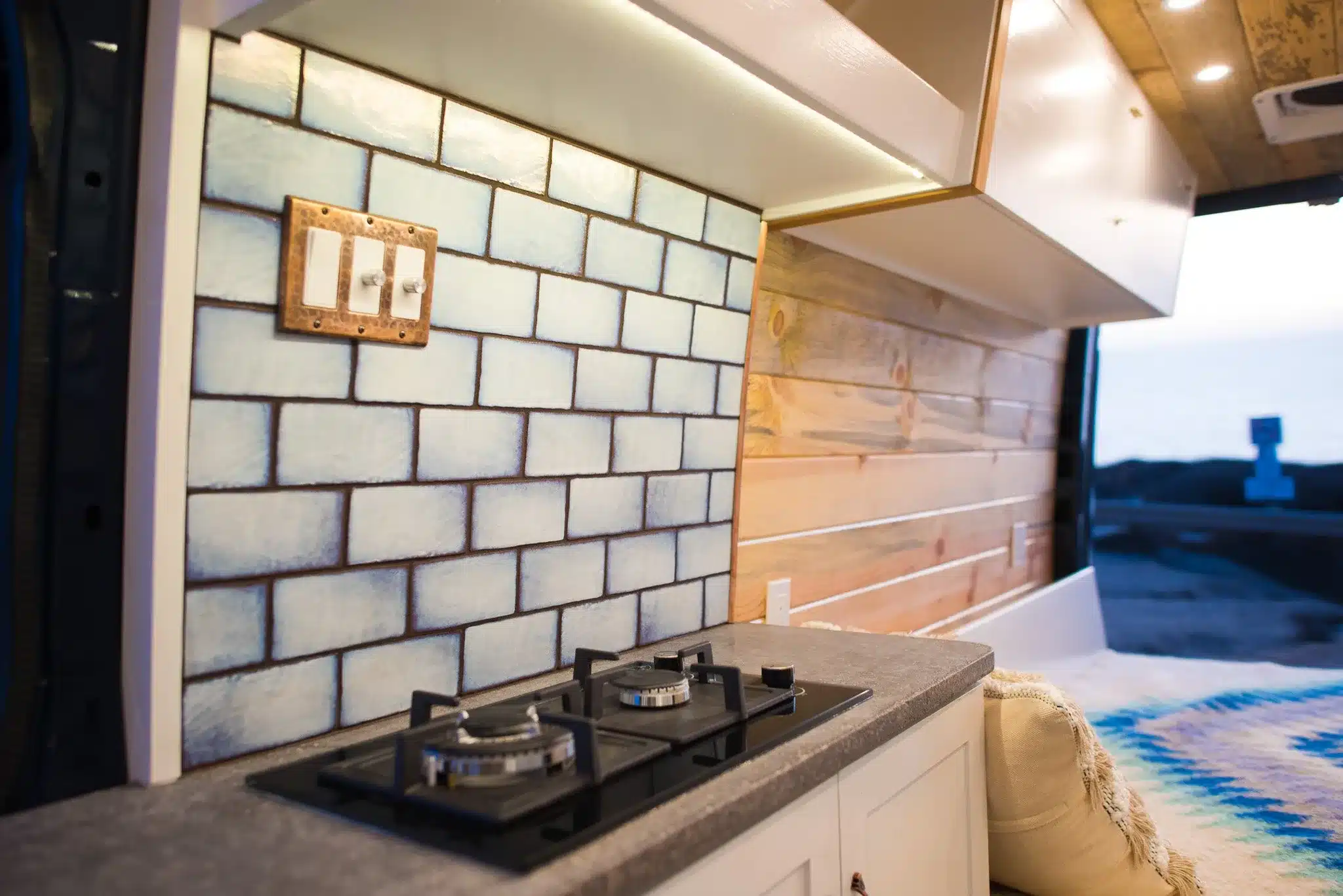 Küchenbereich im Rogue Vans Brooke Campervan mit Gaskocher, Fliesenspiegel und Holzverkleidung