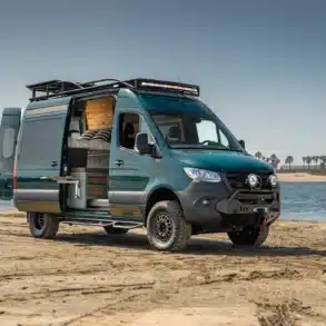Rogue Vans Overlander Campervan mit geöffneten Türen am Strand, Blick auf den Innenausbau und das Flarespace-Bett