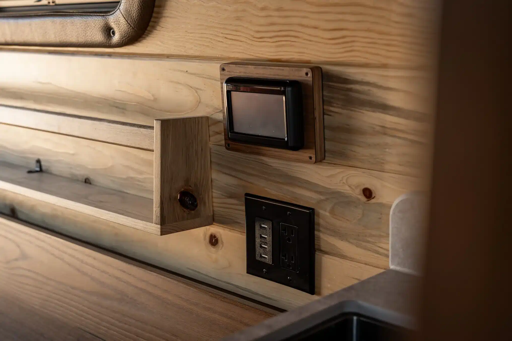 Strom- und USB-Anschlüsse in einer Holzverkleidung im Innenraum eines Rogue Vans Palisade Campervans
