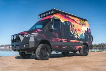 Rogue Vans Summer Classic Campervan mit bunter Folierung und Offroad-Ausstattung am Ufer eines Sees