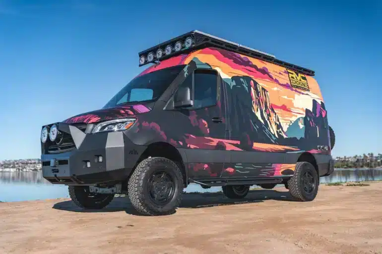 Rogue Vans Summer Classic Campervan mit bunter Folierung und Offroad-Ausstattung am Ufer eines Sees