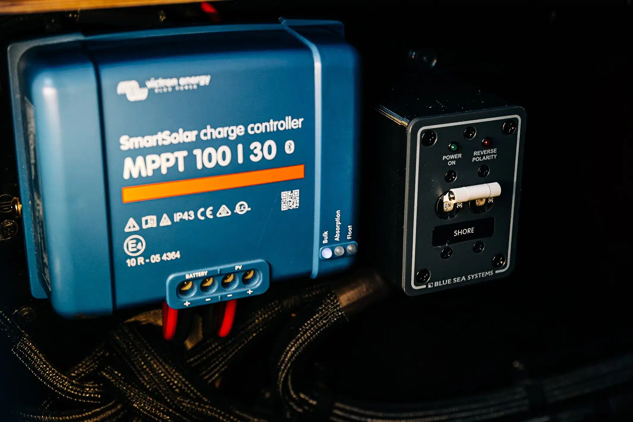 Nahaufnahme eines Victron SmartSolar MPPT 100/30 Ladereglers und eines Blue Sea Systems Schaltpanels im Campervan