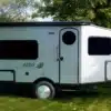 Seitenansicht des Safari Condo Alto A1752 Wohnwagens auf einer Wiese mit Bäumen im Hintergrund