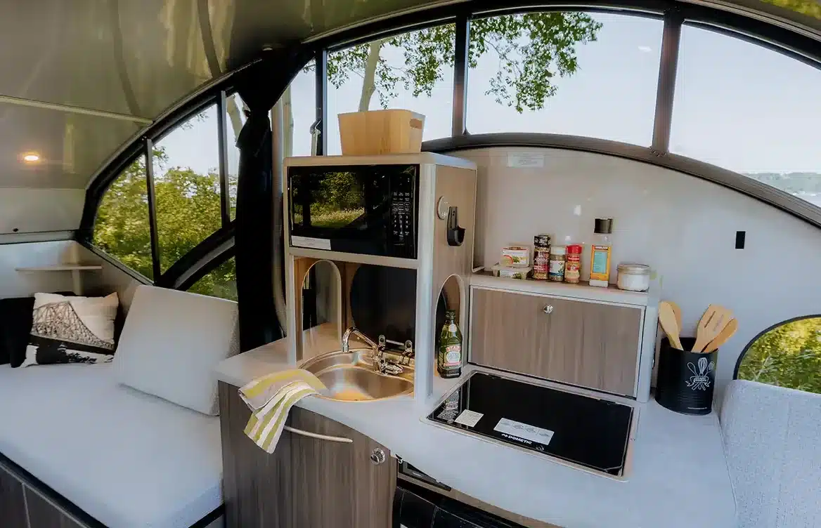 Küchenbereich und Sitzgelegenheit im Innenraum des Safari Condo Alto R1713 Reise-Trailers mit Panoramafenstern
