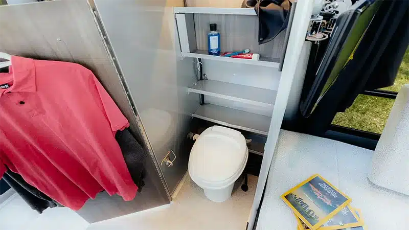 Blick in das Bad des Safari Condo Alto R1713 mit Toilette, Regalen und hängender Kleidung