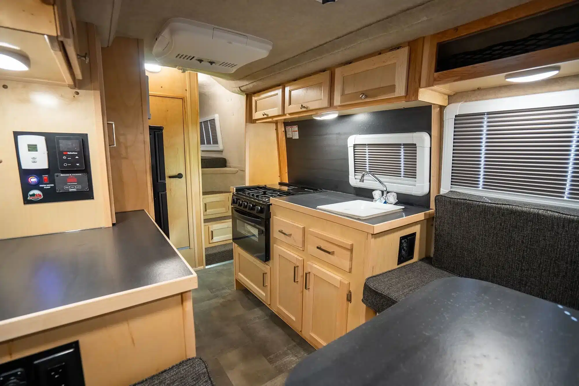 Innenansicht des Scamp 19' Trailers mit Küchenzeile, Sitzbereich und Blick auf das Loftbett