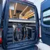 Heckansicht des SUMMIT L1 Vans mit geöffneter Tür, großem Stauraum und zwei Mountainbikes unter dem erhöhten Bett