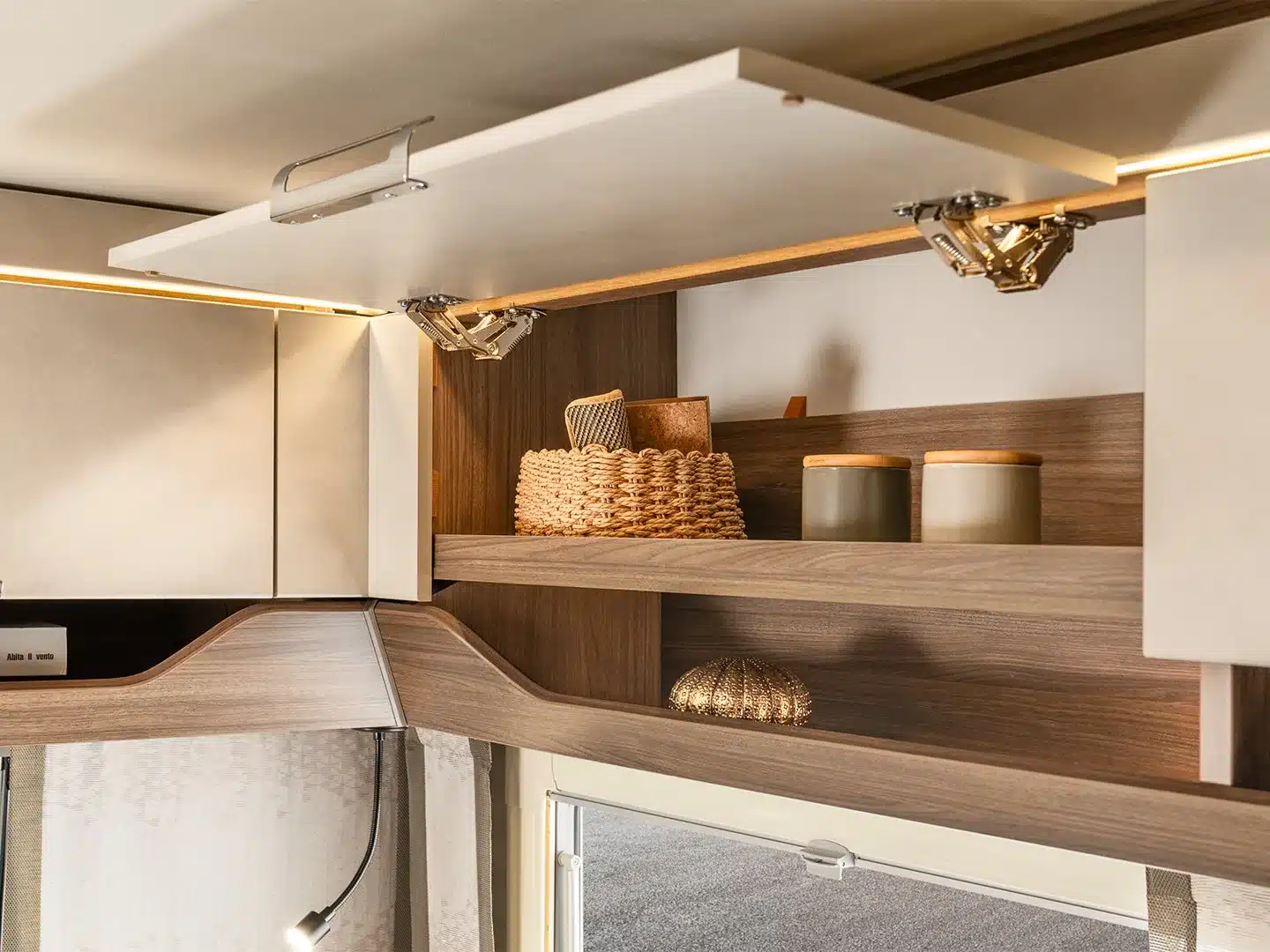 Offenes Staufach mit Ablagen und Deko im Innenraum des TABBERT Cazadora Wohnwagens