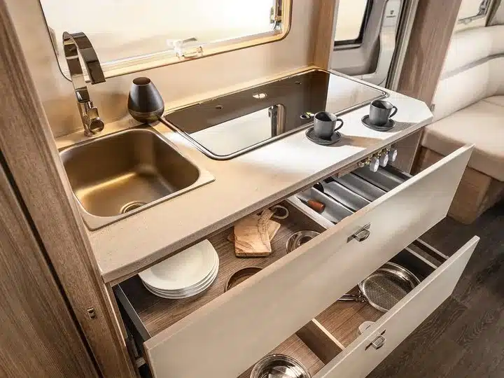 Küchenzeile im TABBERT Cazadora Wohnwagen mit Spüle, Kochfeld und offenen Schubladen mit Geschirr