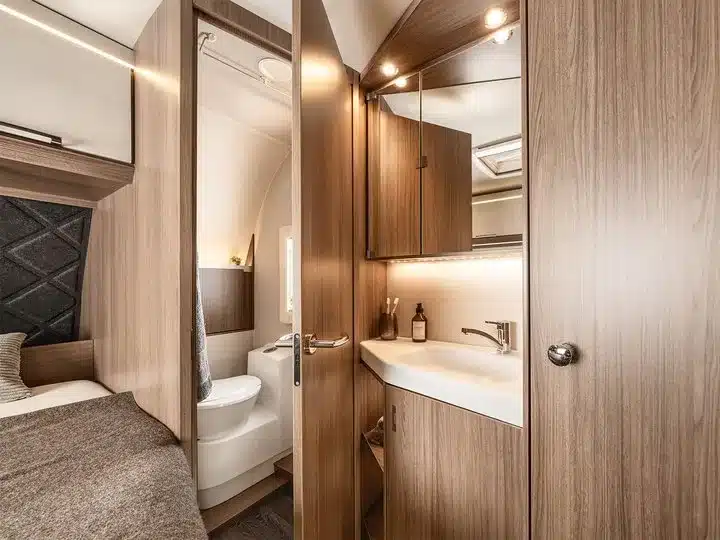 Badezimmer im TABBERT Cazadora Wohnwagen mit Waschbecken, Spiegel, Holzdekor und Toilette