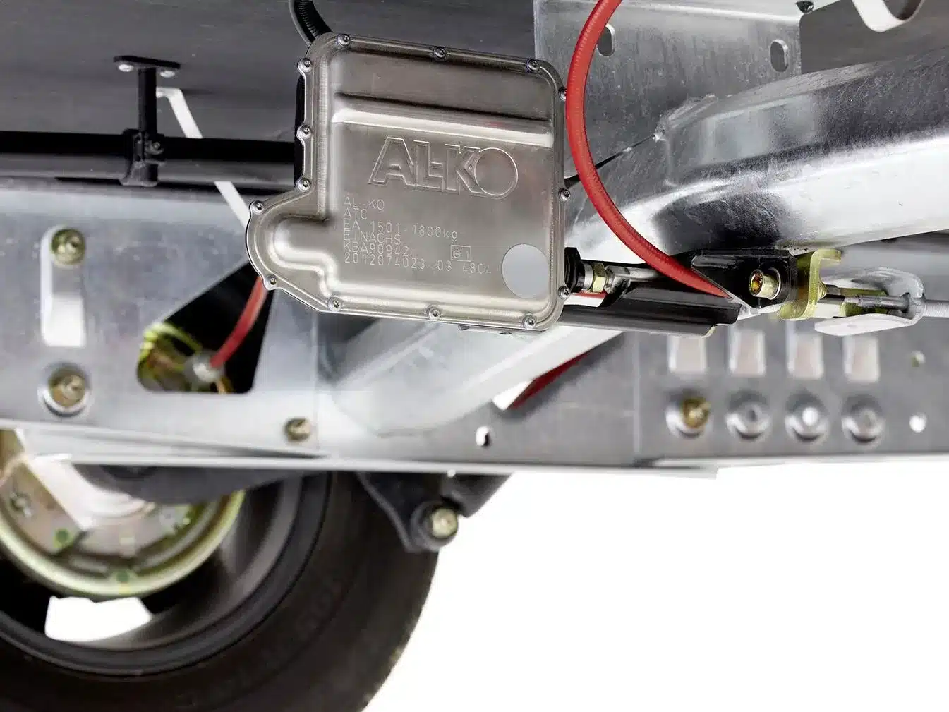Nahaufnahme des AL-KO Fahrwerks unter einem Wohnwagen mit sichtbaren Kabeln und Metallteilen