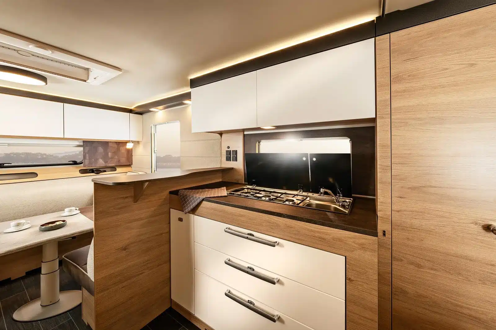 Innenansicht eines Tabbert Pantiga Finest Edition Wohnwagens mit moderner Küche, Sitzgruppe und viel Stauraum