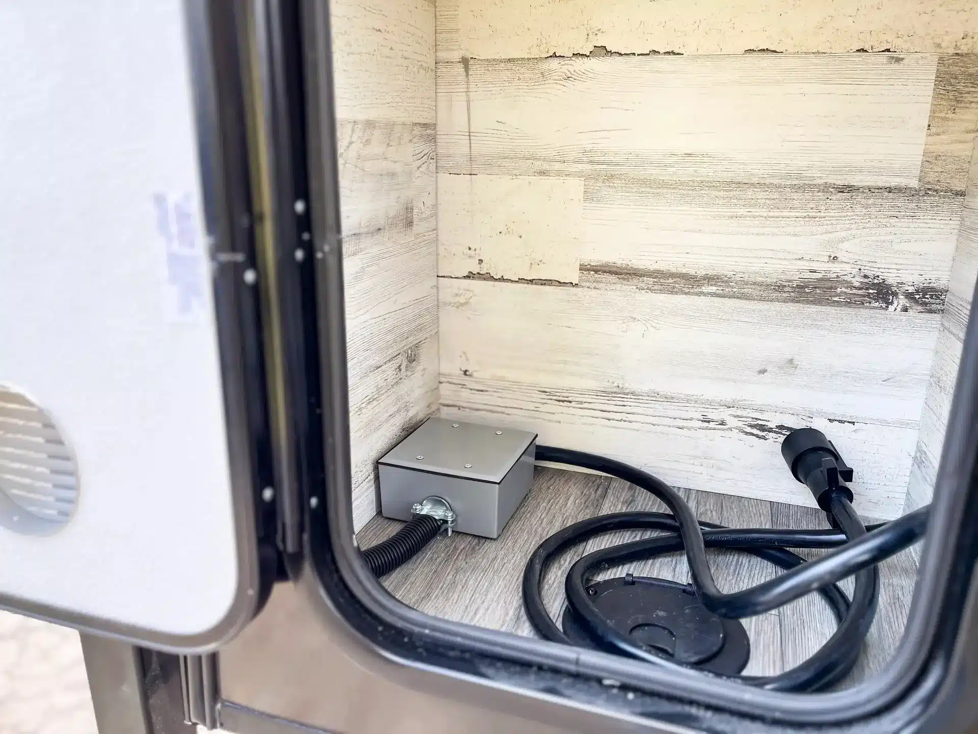 Stromanschluss und Kabel im Außenstauraum eines Truck Campers mit Holzdekor