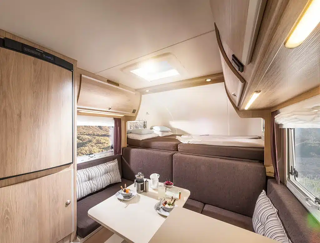 Innenansicht einer Tischer Trail/Box 280 Wohnkabine mit Sitzgruppe, Tisch, Alkovenbett und Stauraum