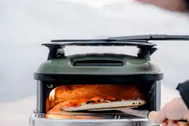 Mobiler Outdoor-Gasofen Tread mit Pizza auf Pizzaschaufel im Freien