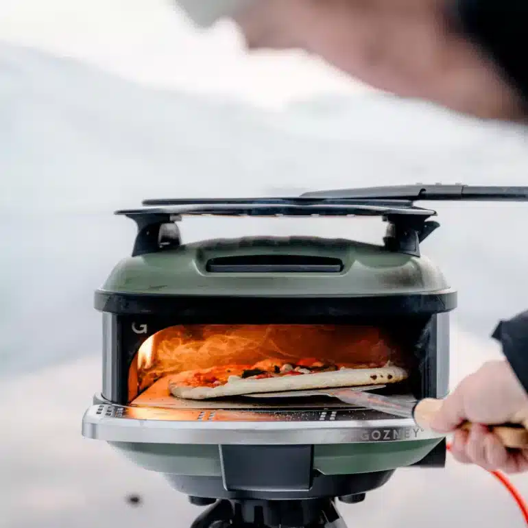 Mobiler Outdoor-Gasofen Tread mit Pizza auf Pizzaschaufel im Freien