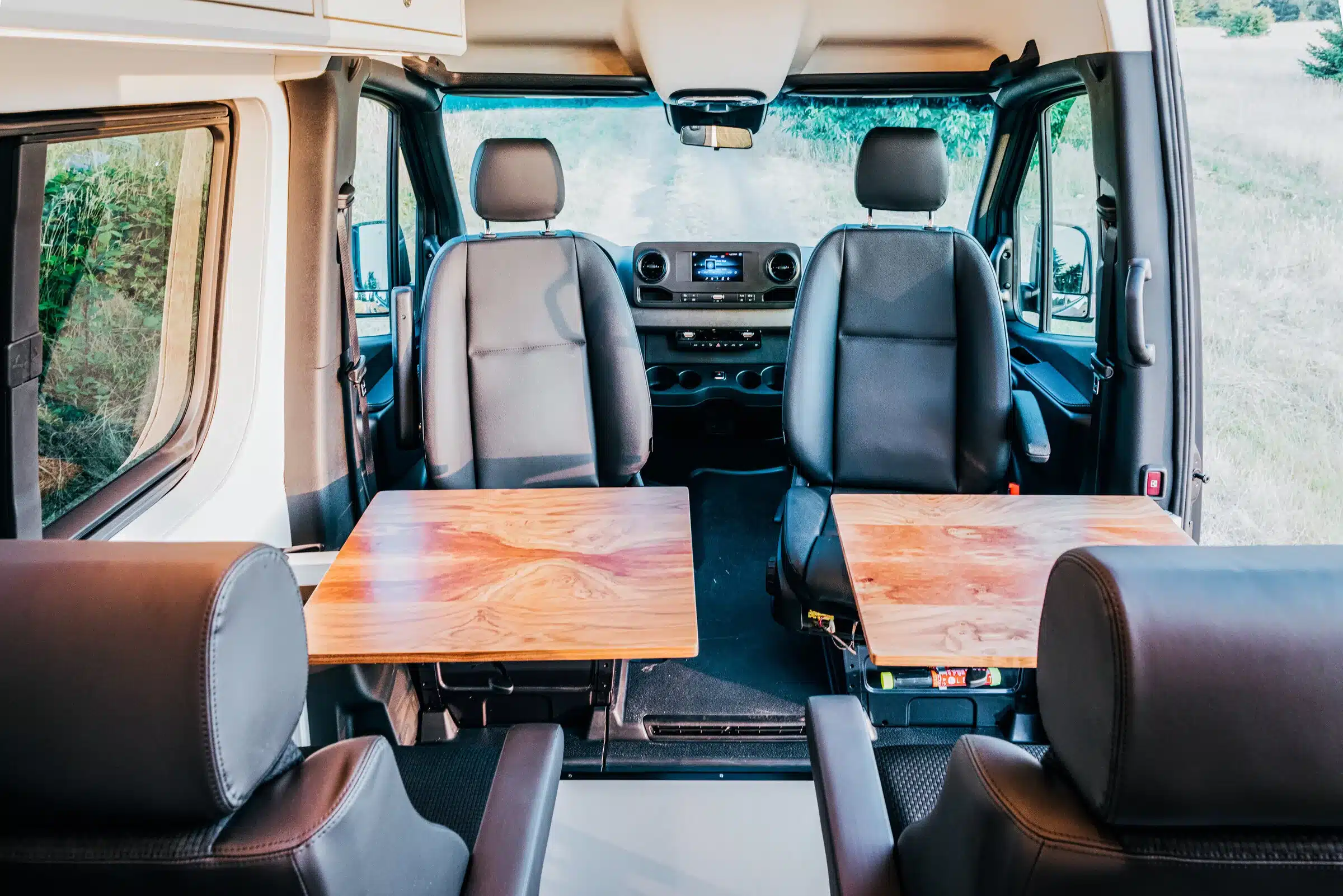 Blick in den Innenraum eines Tree House Sprinter 4x4 mit drehbaren Einzelsitzen und zwei Walnussholz-Tischen