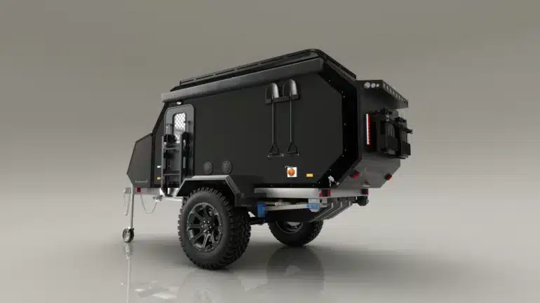 Schwarzer Valkari X1 Offroad-Caravan mit großen Reifen, Schaufeln an der Seite und robustem Aufbau auf hellem Hintergrund