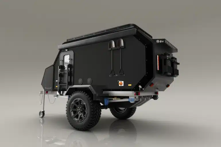 Schwarzer Valkari X1 Offroad-Caravan mit großen Reifen, Schaufeln an der Seite und robustem Aufbau auf hellem Hintergrund