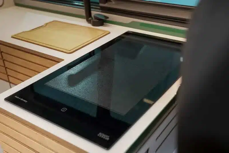 Eingebautes VANING Induktionskochfeld mit schwarzer Schott Ceran Glasoberfläche in einer modernen Campervan-Küche