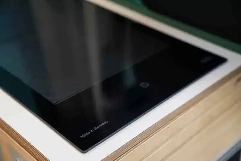 Nahaufnahme eines eingebauten VANING Induktionskochfelds mit schwarzer Glasoberfläche und Bedienfeld, eingebaut in eine Küchenarbeitsplatte aus Holz