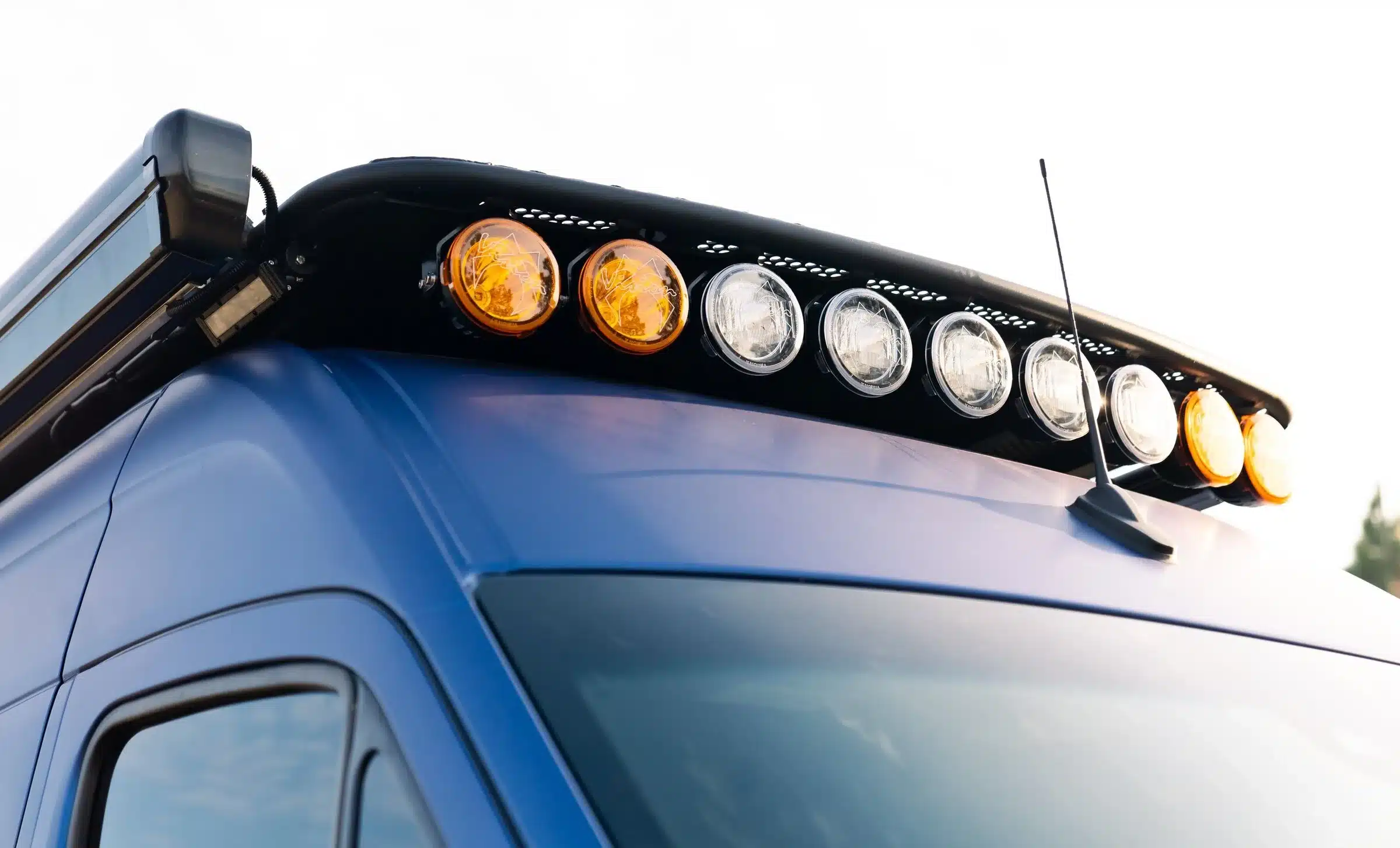 Nahaufnahme von Zusatzscheinwerfern und Dachträger auf einem navyblauen Mercedes Sprinter 4x4