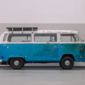 Seitenansicht eines blau-weißen VW T2b mit sichtbaren Brandschäden, restauriert nach dem Feuer in Südkalifornien