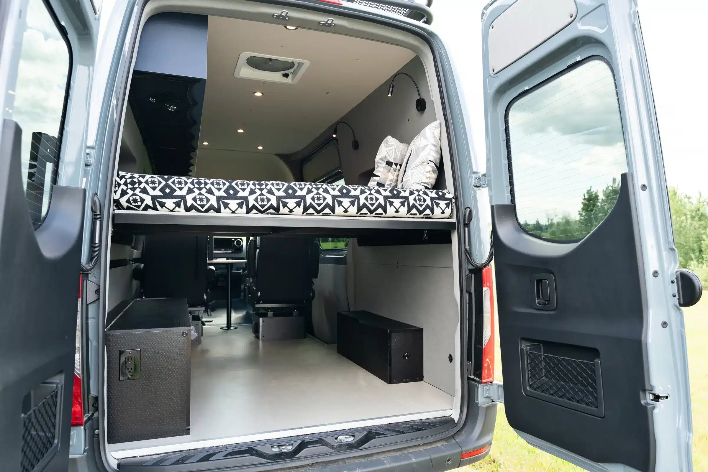 Innenansicht eines ausgebauten 2019 Mercedes Sprinter 4x4 mit Bett und Stauraum, fotografiert von hinten bei geöffneter Hecktür