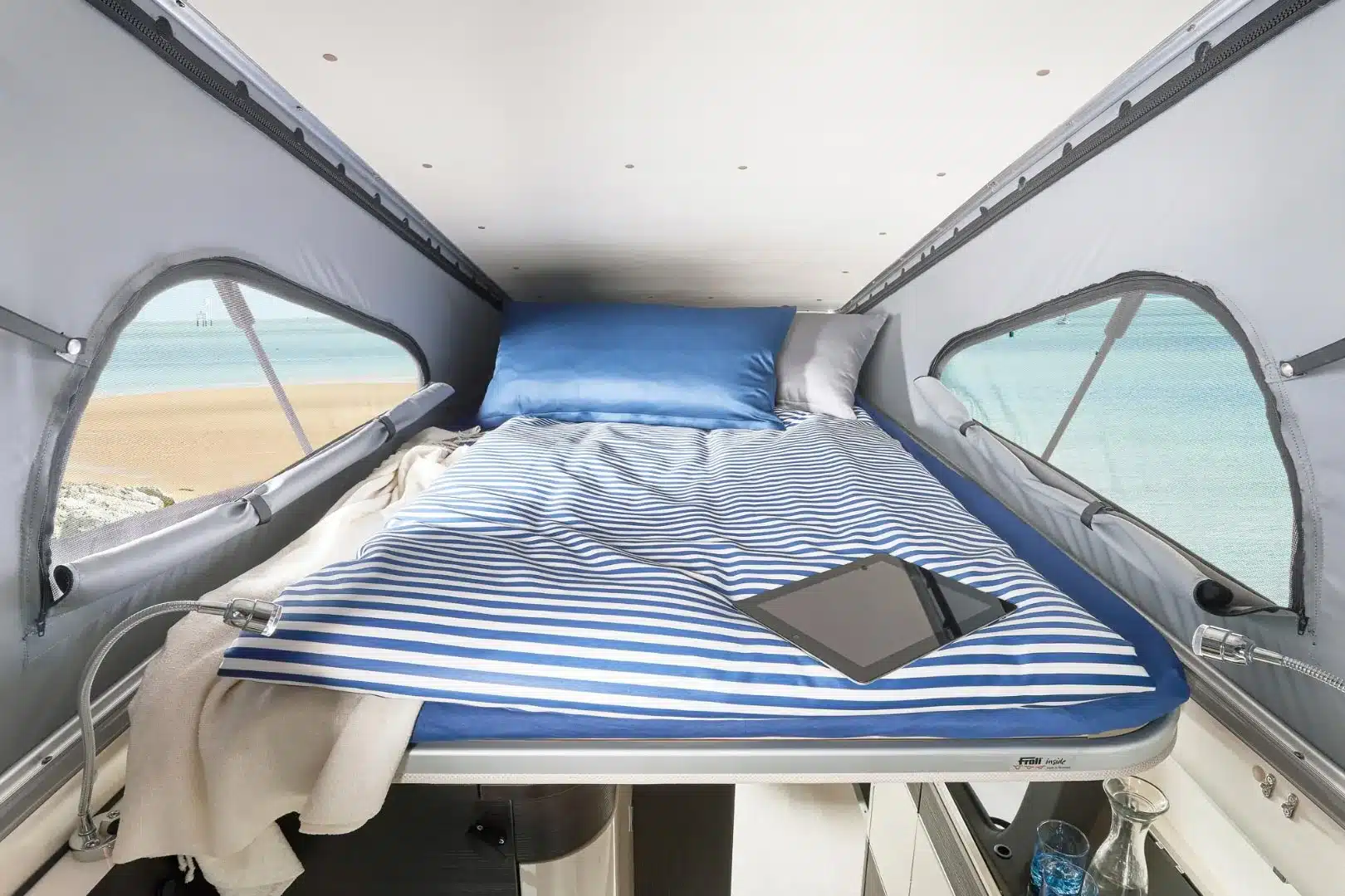Innenansicht des Schlafbereichs im Aufstelldach eines Westfalia Jules Verne Campervans mit Blick auf den Strand