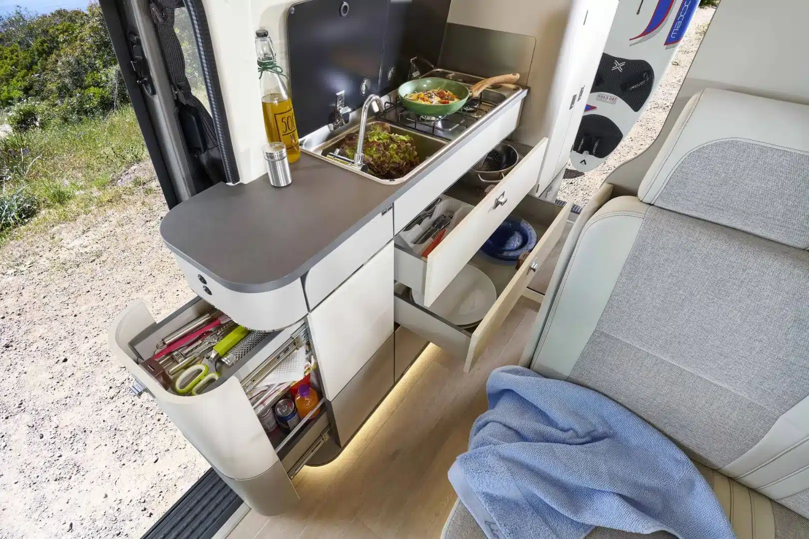 Innenansicht der Küchenzeile im Westfalia Kepler One mit Gasherd, Spüle, Arbeitsfläche und geöffneten Schubladen