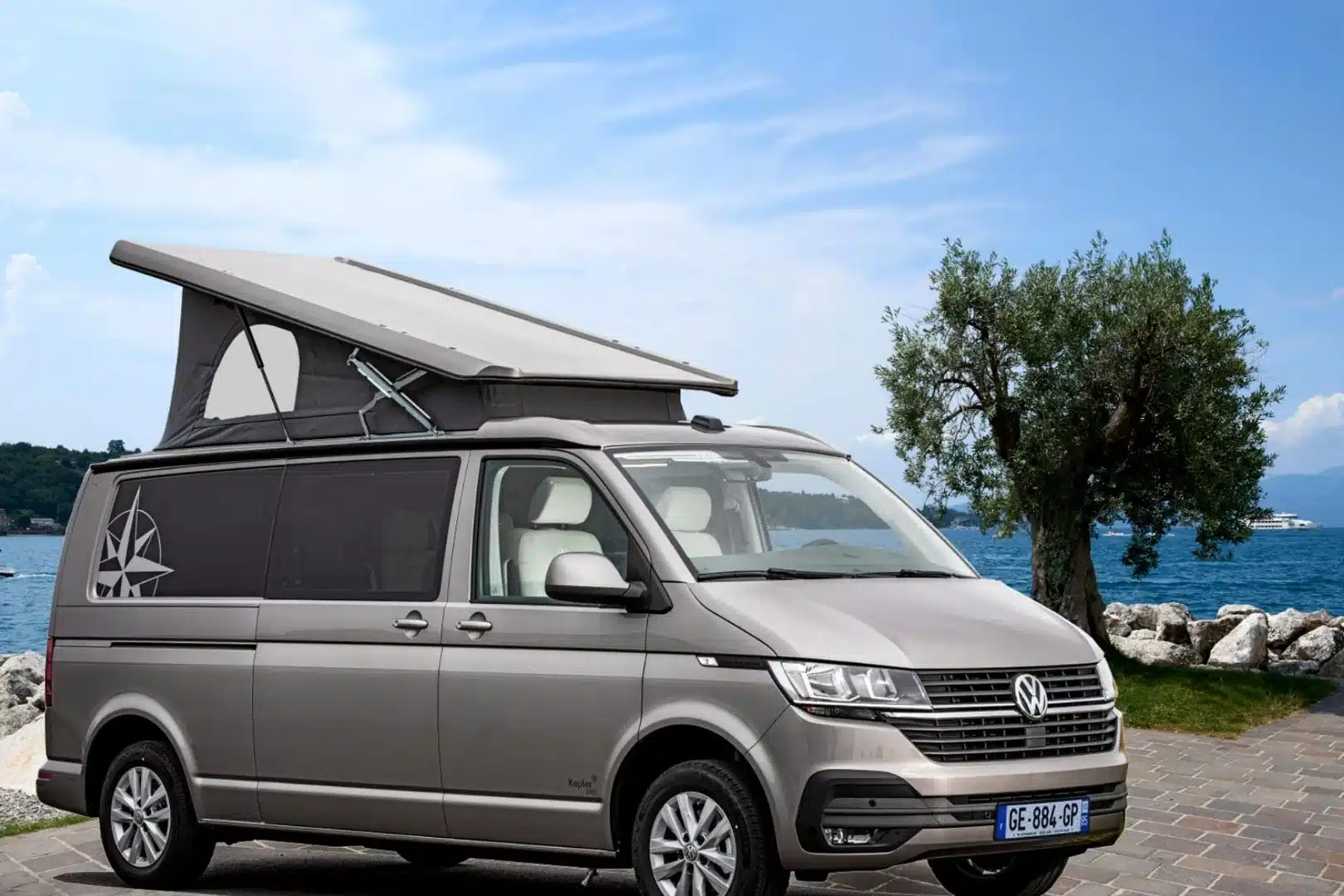 Westfalia Kepler One Campervan mit ausgeklapptem Hochdach, geparkt am Seeufer mit Baum im Hintergrund