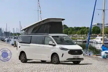 Weißer Westfalia Kipling Campervan mit geöffnetem Aufstelldach steht am Hafen neben Segelbooten