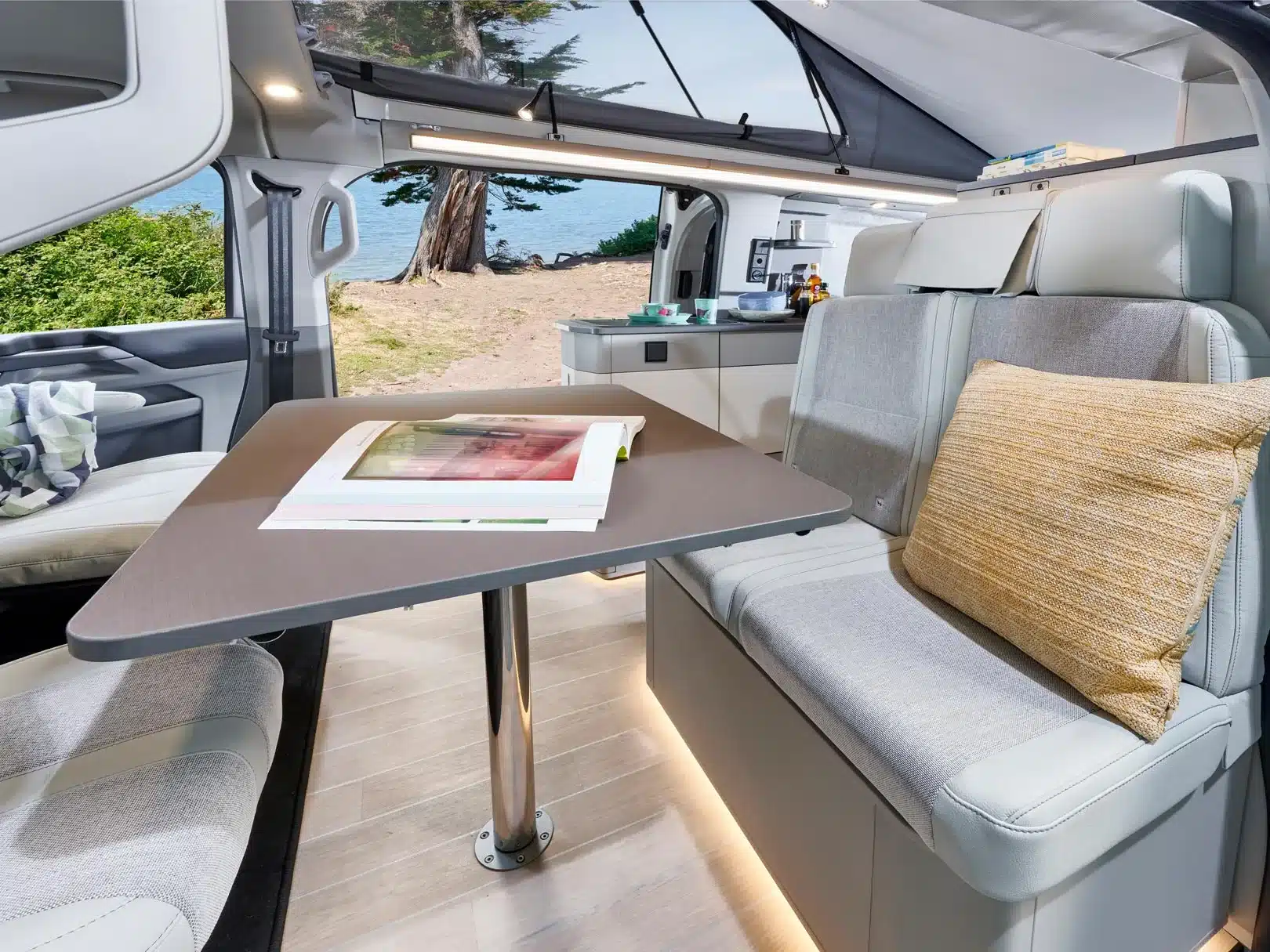 Innenansicht des Westfalia Kipling Campervans mit Sitzgruppe, Tisch und Küchenzeile, Blick nach draußen