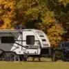 Winnebago Micro Minnie Wohnwagen mit schwarzem Pick-up vor herbstlicher Waldkulisse