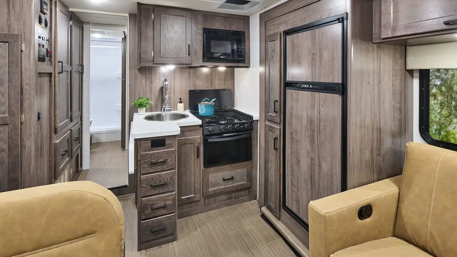 Küche und Wohnbereich im Winnebago Minnie Winnie NPF Wohnmobil mit Holzdekor, Spüle, Herd, Mikrowelle und Kühlschrank