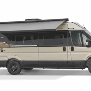 Seitenansicht eines beige-schwarzen Winnebago Travato Kastenwagen-Campers mit ausgefahrener Markise