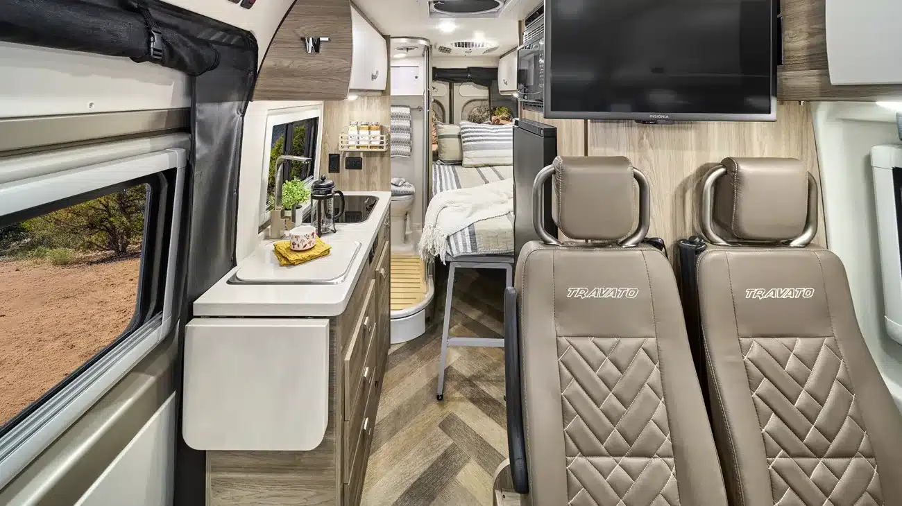 Innenansicht eines Winnebago Travato Campervans mit Küche, Sitzplätzen und Schlafbereich