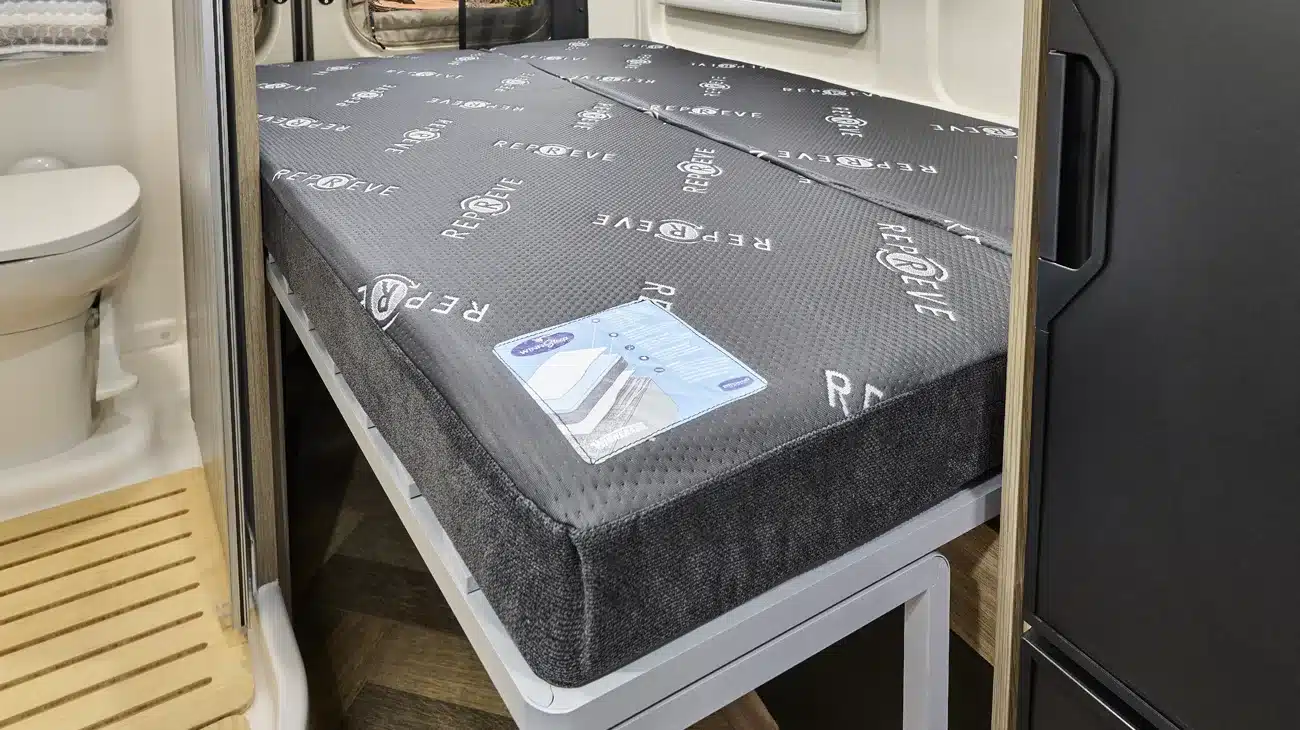 Blick auf das Bett und die Nasszelle im Innenraum eines Winnebago Travato Kastenwagen-Campers