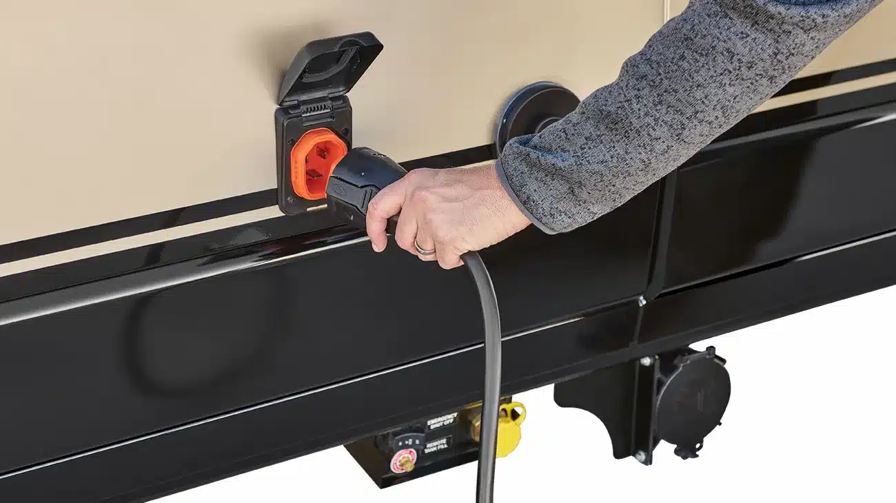 Hand steckt Stromkabel in den Außenanschluss eines Winnebago Travato Campervans