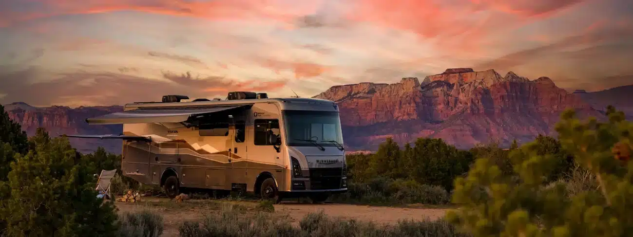 Winnebago Vista NPF Wohnmobil mit Nationalpark-Design steht vor beeindruckender Felslandschaft im Sonnenuntergang